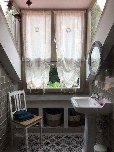a bathroom with a sink and a window with a mirror at Ferienwohnung Kamp "Blick ins Grüne" in Potsdam