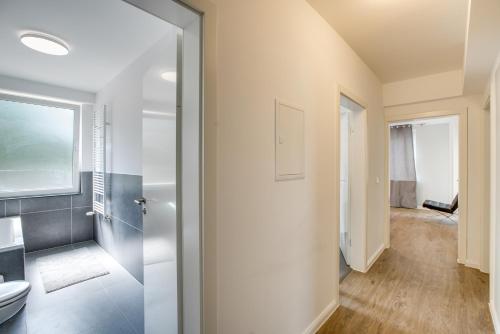 Stay Here ND Apartments في كريفيلد: حمام مع مرحاض وباب زجاجي