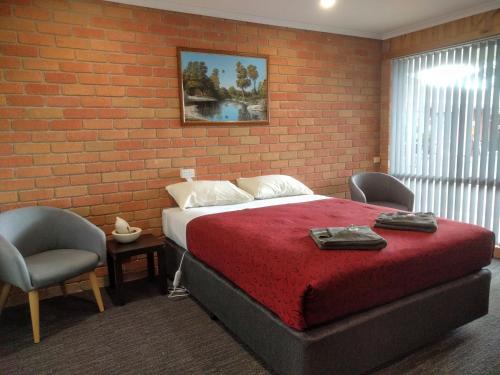 a bedroom with a bed and a brick wall at Travellers Inn Kaniva in Kaniva