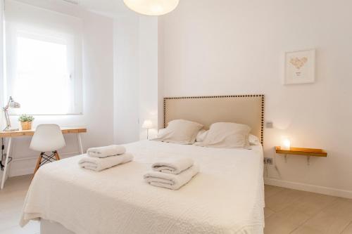 een witte slaapkamer met een bed met handdoeken erop bij R&C APARTMENTS CLOSE to CENTER in Valencia