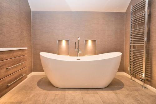 a bathroom with a large white tub in a room at The Old Chequers - Hot tub & Games room in Fakenham