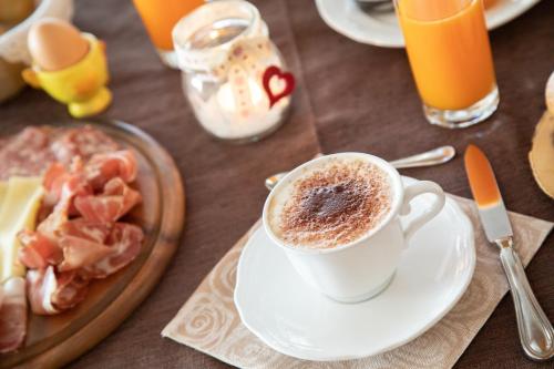 a table with a cup of coffee and a plate of food at Hotel Siror in Fiera di Primiero