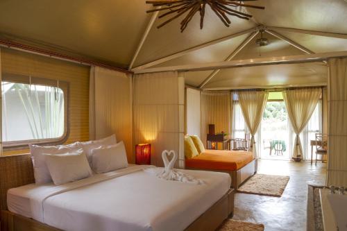 a bedroom with a bed and a chair in a room at Pai Vimaan Resort in Pai