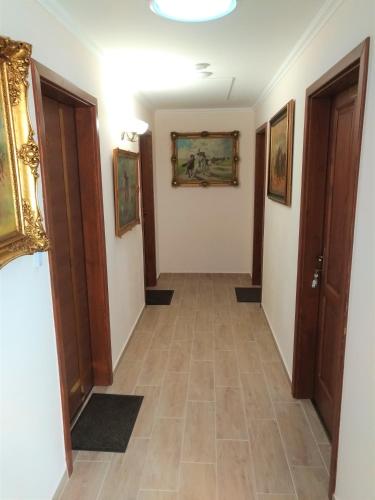 a hallway with paintings on the walls and a tile floor at St. Hubert Vendégház in Hortobágy