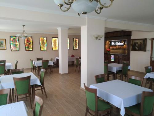 a dining room with white tables and green chairs at St. Hubert Vendégház in Hortobágy