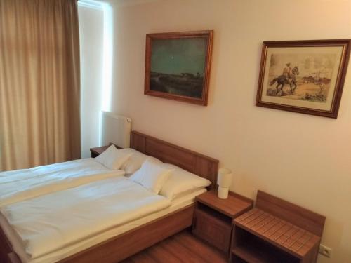 a bed in a bedroom with a picture on the wall at St. Hubert Vendégház in Hortobágy