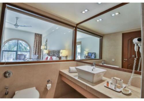 ein Badezimmer mit einem Waschbecken und einem großen Spiegel in der Unterkunft Neelams The Grand Hotel in Calangute