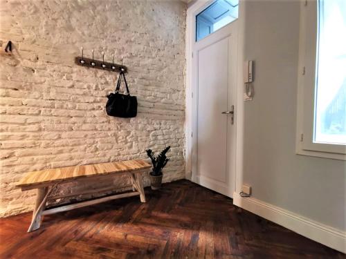 a hallway with a wooden bench next to a brick wall at Le bon'appart - 50m de la cathédrale in Montauban