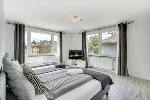 a bedroom with two beds and a tv and two windows at Stay Here ND Apartments in Krefeld