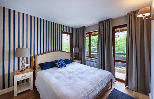 a bedroom with a bed and a large window at Predela LUX Aparthotel in Bansko