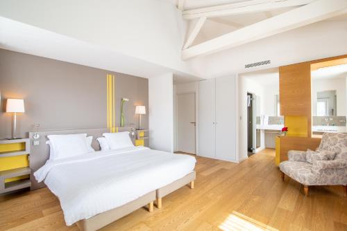 a bedroom with a large white bed and a chair at Hotel Itsas Mendia in Bidart