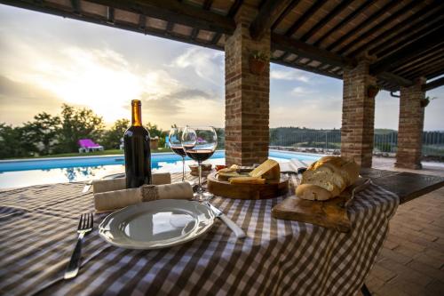 a picnic table with a glass of wine and cheese at La Coppa in Asciano