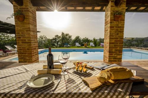 a picnic table with wine and cheese next to a pool at La Coppa in Asciano