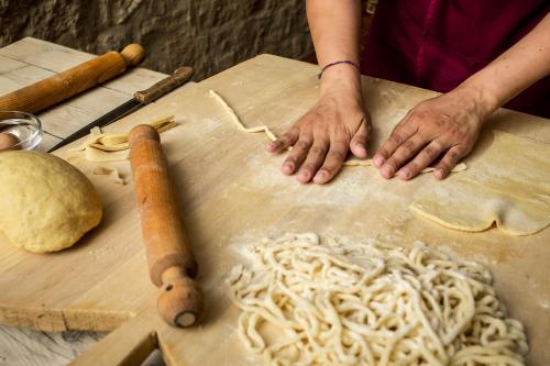 a person is preparing noodles on a cutting board at La Coppa in Asciano