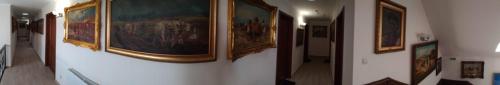 a group of paintings on a wall in a hallway at St. Hubert Vendégház in Hortobágy