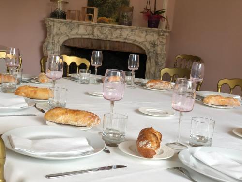 een tafel met borden met eten en glazen wijn bij La villa rochette in Forges-les-Bains