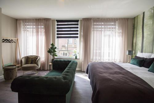 a bedroom with a bed and a couch and a window at Citystays Deventer in Deventer