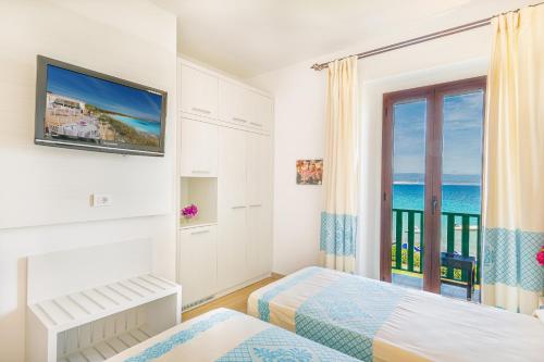 a bedroom with two beds and a window with the ocean at Hotel Dei Pini in Alghero