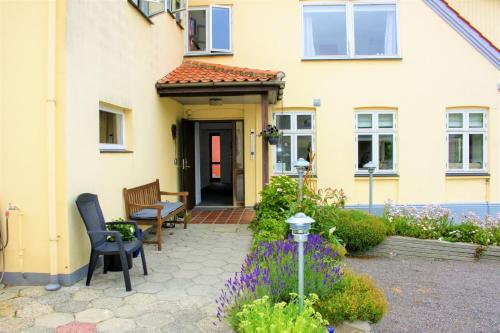 a yellow house with a table and chairs and flowers at NORDVIG bed & breakfast in Sandvig