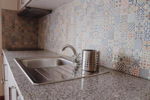 un fregadero de acero inoxidable en una cocina con papel pintado en Oportocean Suites en Matosinhos
