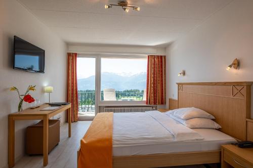 um quarto de hotel com uma cama e uma grande janela em Hôtel Splendide em Crans-Montana