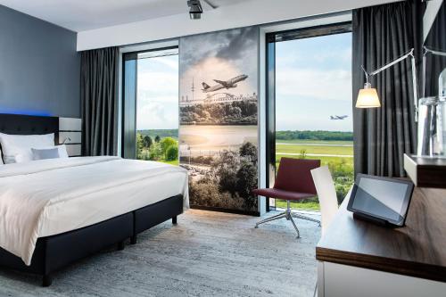 a hotel room with a bed and a large window at Airport Plaza Hotel Hamburg in Norderstedt