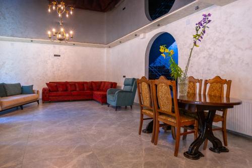 a living room with a red couch and a table and chairs at Guesthouse David Zhorzholiani in Mestia