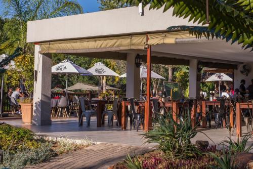 a patio with tables and chairs and umbrellas at Kruger Park Lodge Unit No. 524 in Hazyview