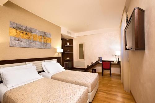 um quarto de hotel com duas camas e uma secretária em Breaking Business Hotel em Mosciano SantʼAngelo