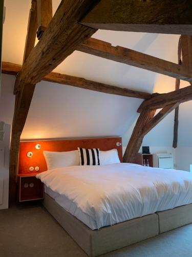 um quarto com uma cama grande e vigas de madeira em Fitz Roy Urban Hotel, Bar and Garden em Maastricht