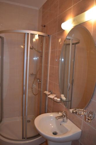 a bathroom with a shower and a sink and a mirror at Pensiunea Magura in Baia Mare
