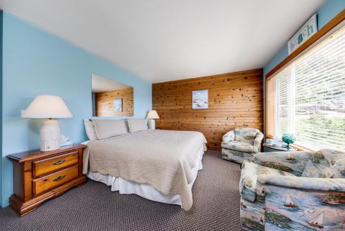 ein Schlafzimmer mit einem Bett, einem Stuhl und einem Fenster in der Unterkunft Whale-come Home in Depoe Bay