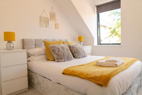 a white bedroom with a large bed with a yellow blanket on it at Town Centre Lodge in Huntingdon