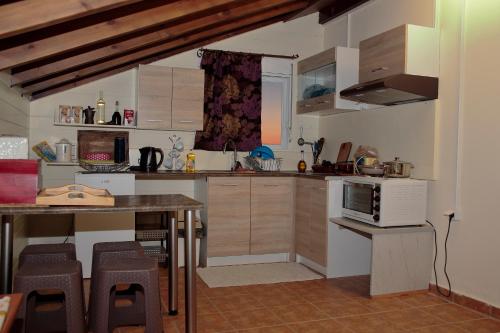 a kitchen with wooden cabinets and a table with chairs at Alexandra Homestay in Kalavárda