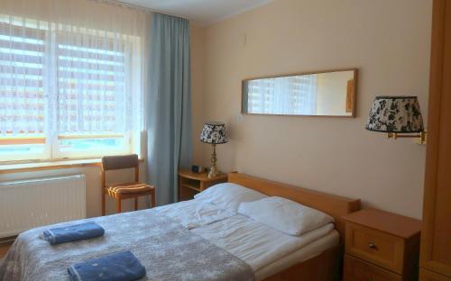 a bedroom with a bed and a mirror and a window at Pokoje Gościnne OAZA in Sztutowo