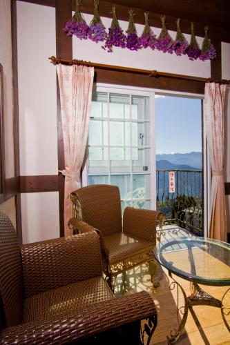 a balcony with chairs and a glass table and a window at Maple Leave Holiday Villa in Renai