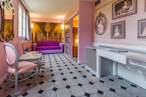 a pink room with a purple couch and a table at Explorers Hotel Marne-la-Vallée in Magny-le-Hongre