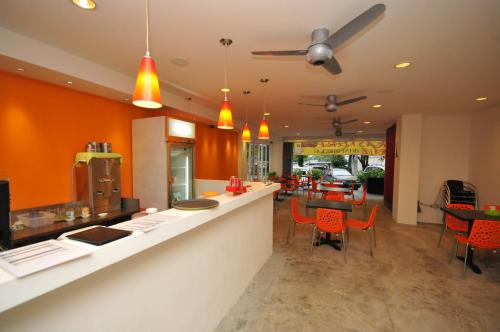 a kitchen with orange walls and a bar with chairs at M Design Hotel @ Pandan Indah in Kuala Lumpur