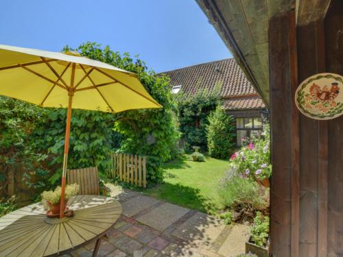 AylmertonにあるHoliday Home The Roostの庭のテーブルに座る黄色の傘