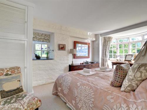 een slaapkamer met een groot bed en een stoel bij Holiday Home Trevose in Padstow