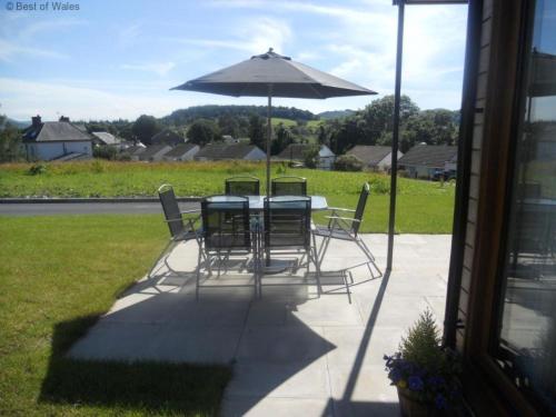 a table and chairs with an umbrella on a patio at Holiday Home Ty Pennal by Interhome in Pennal
