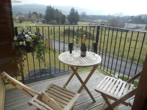 a table with two chairs and a bottle of champagne on a balcony at Holiday Home Ty Pennal by Interhome in Pennal