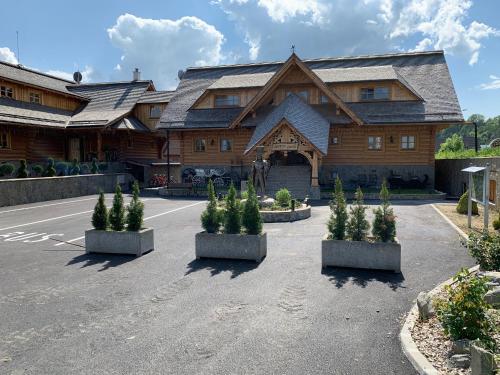 a large building with trees in front of it at Zbojnicky penzion in Oravska Jasenica