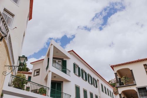 a white building with green shutters and balconies at Vila Mar Apartment in Ponta do Sol