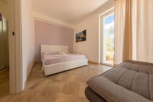 a bedroom with a bed and a couch and a window at Tenuta Ciullo in Marina di Pescoluse