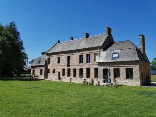 a large brick building on a grass field at Manoir des Carreaux Chambres d'hôtes in Ingouville