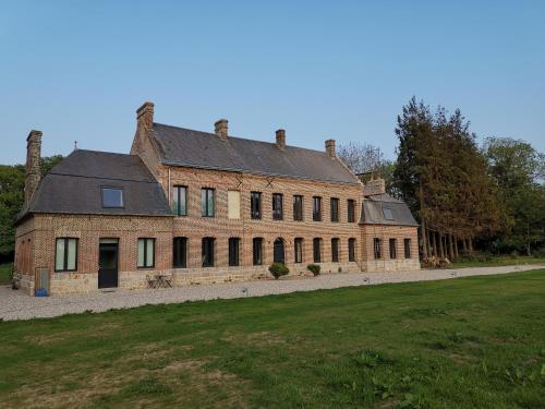a large brick building with a field in front of it at Manoir des Carreaux Chambres d'hôtes in Ingouville