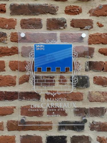 a sign on the side of a brick wall at Manoir des Carreaux Chambres d'hôtes in Ingouville