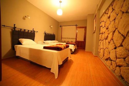 1 dormitorio con 2 camas y pared de piedra en Nemrut Kervansaray Hotel, en Karadut