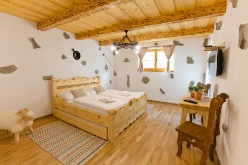 a bedroom with a wooden bed and a table at Zbojnicky penzion in Oravska Jasenica